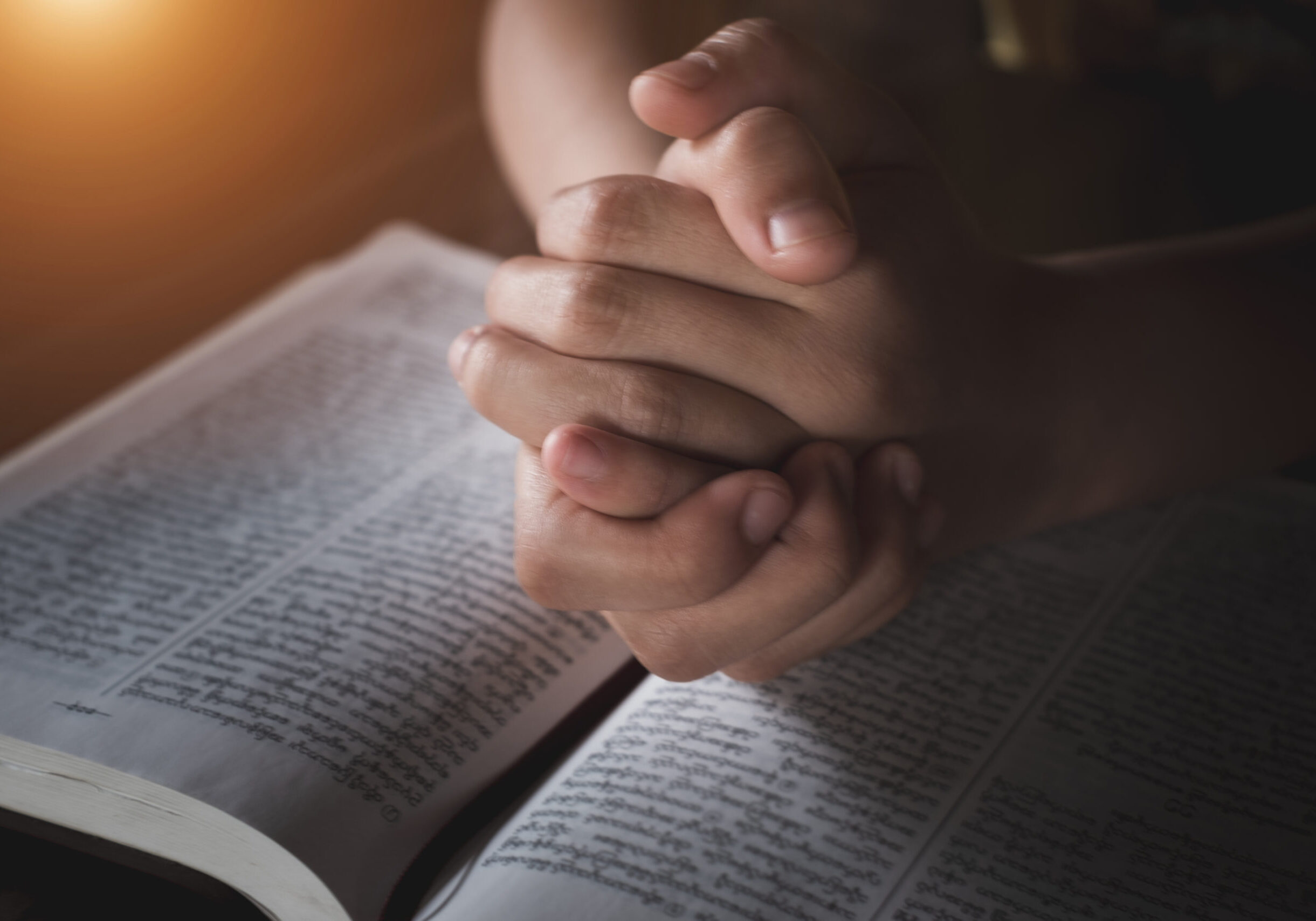 A young woman sat and studied the scriptures laid on a wooden table. The educational concept of the Christian Tripitaka that is open and praying to God Faith in the divine power of God. Bible study.